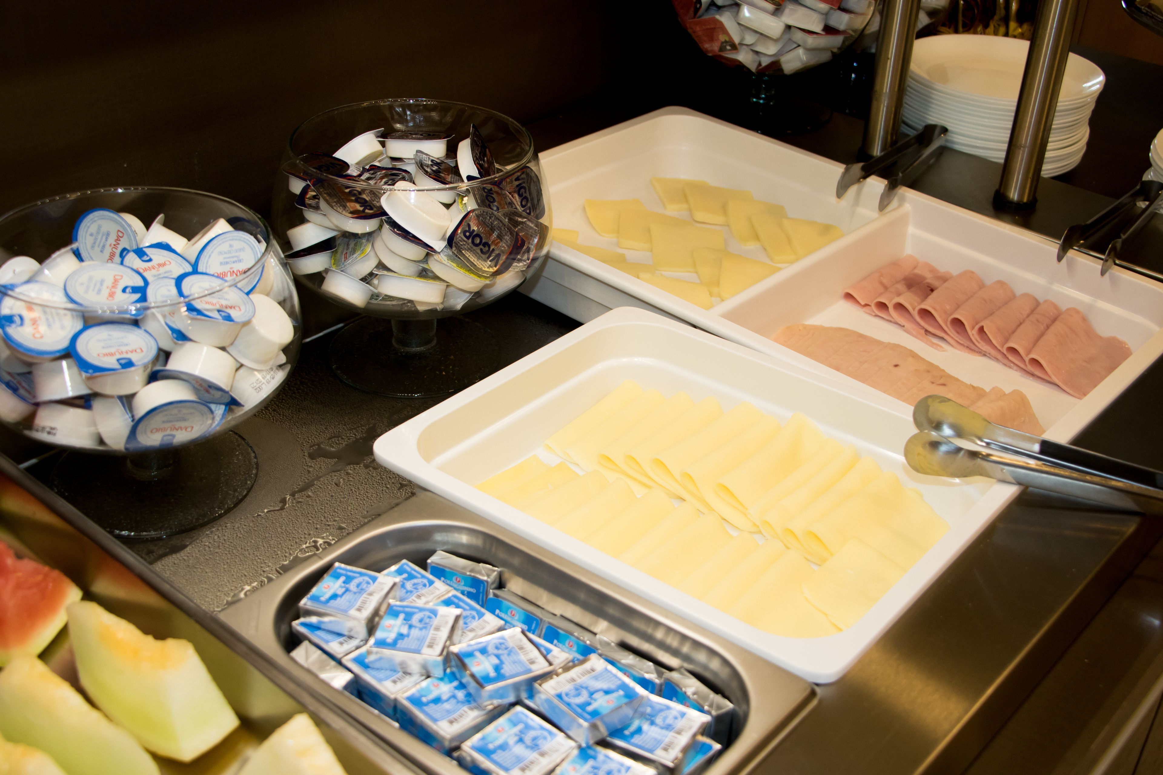 Ein Buffet mit verschiedenen Speisen, darunter Käse, Schinken und verpackten Produkten.