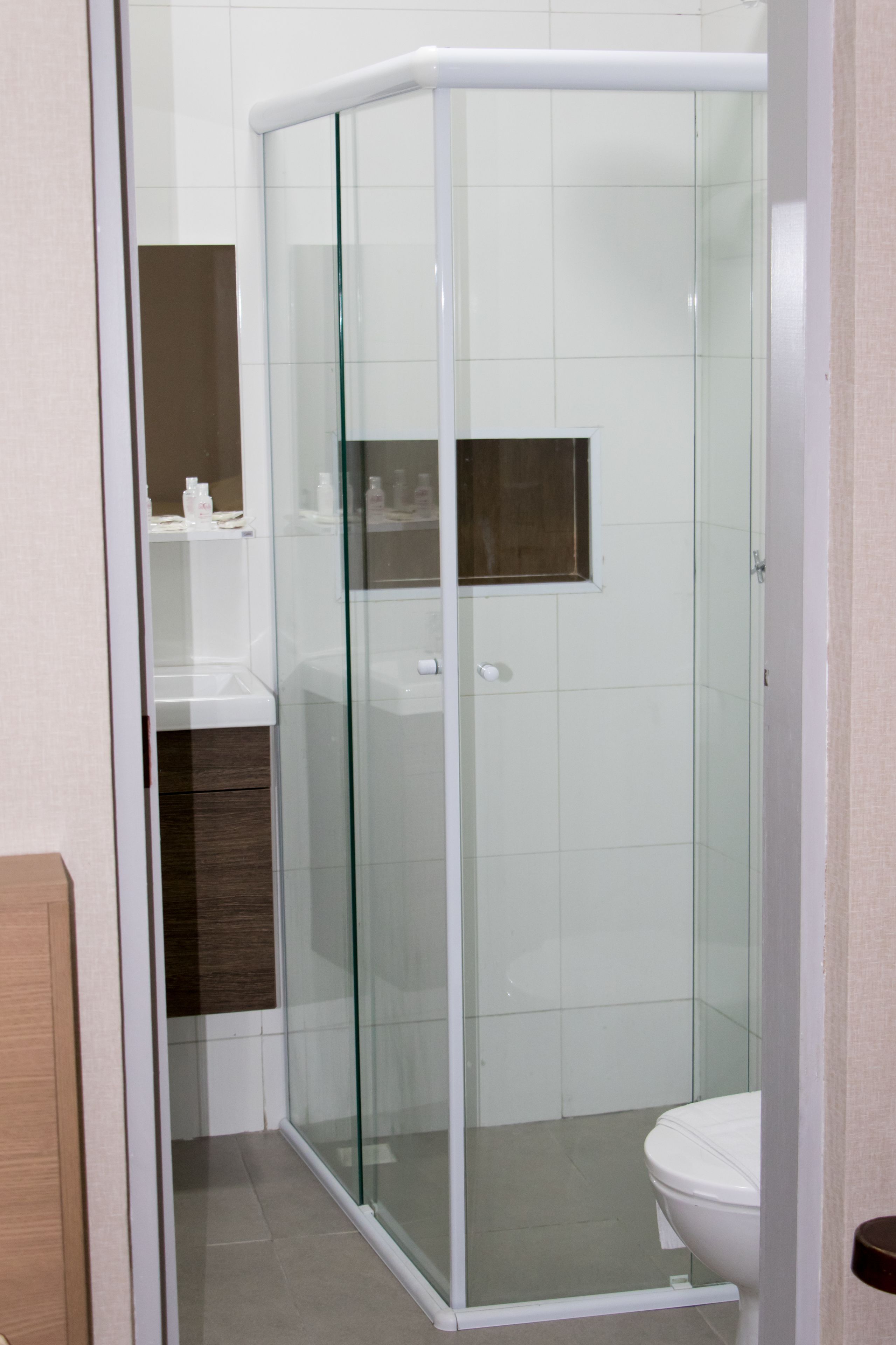 A modern bathroom with a glass-enclosed shower, a white toilet, and a wooden vanity with a mirror.