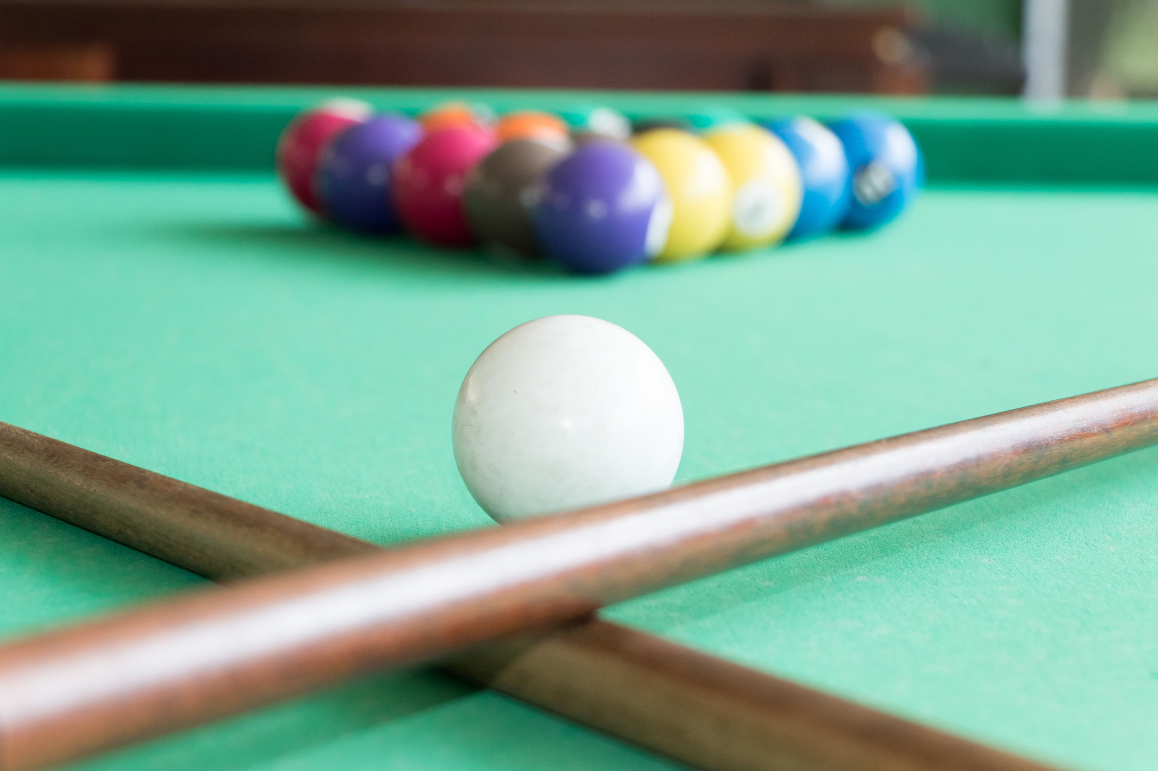 A pool table with a white cue ball and a striped cue stick.