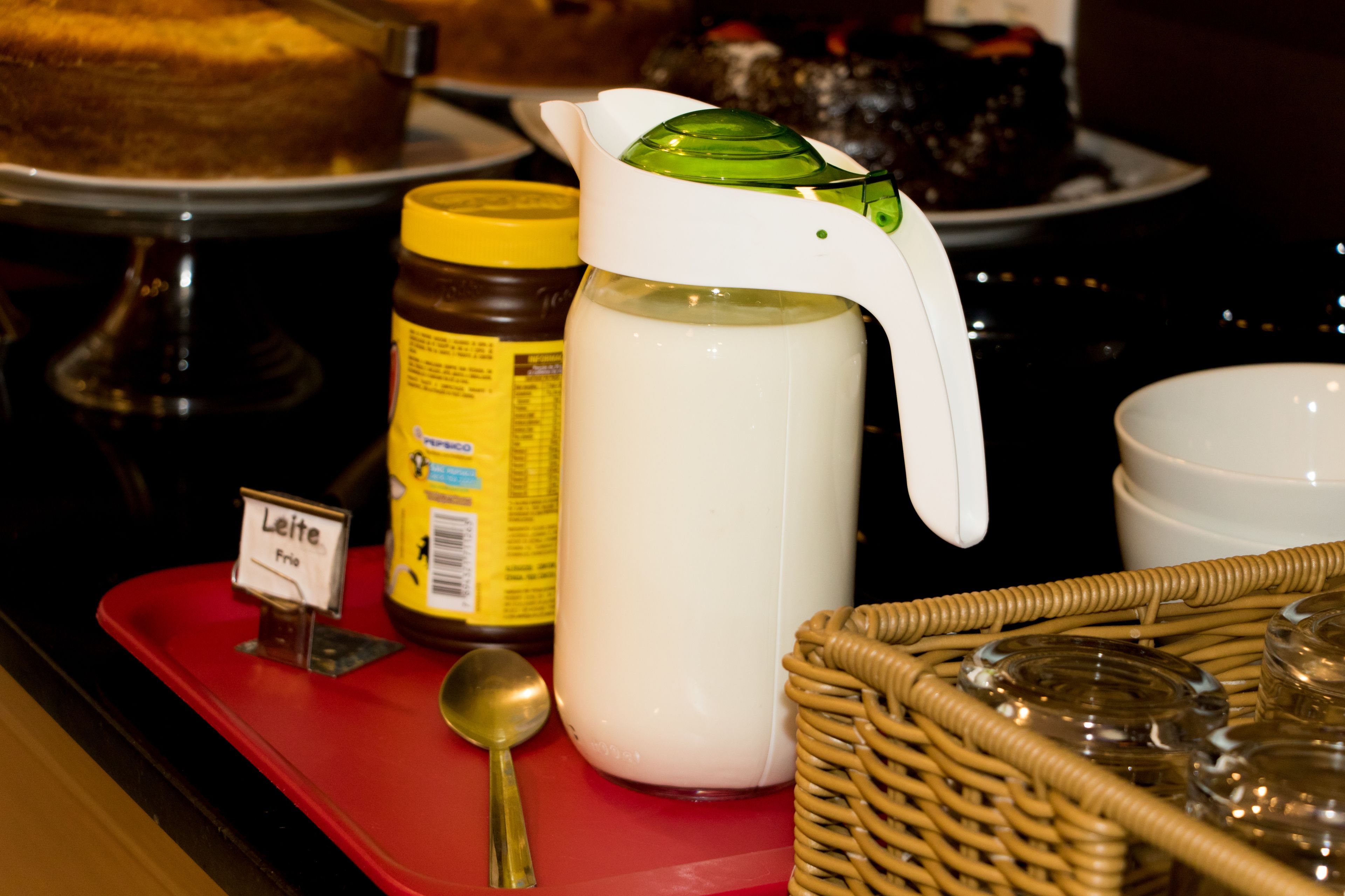 A tray with a milk jug, a jar of honey, and a sign indicating 'Leite Frio'.