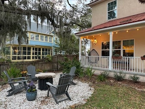 A patio with Adirondack chairs, a round table, and a small fire pit.