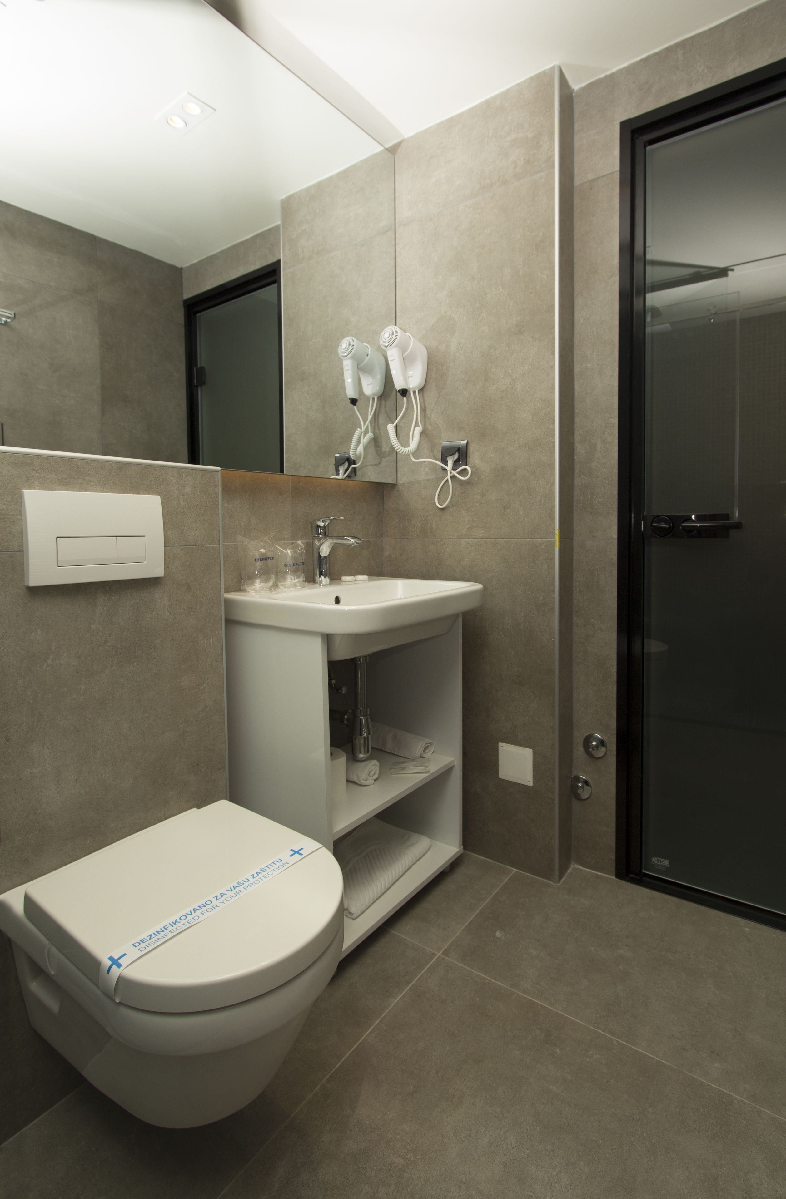Une salle de bain moderne équipée de toilettes, d’un lavabo et d’un sèche-cheveux.