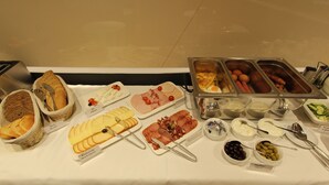 A buffet with various food items including bread, cheese, ham, sausages, and olives. - Garni Hotel Boutique 25h (Niš)