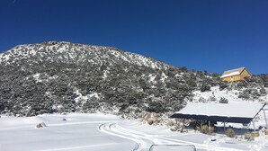 A snow-covered landscape with a mountain, a house, and solar panels. - Hike By Light, Campers Delight. (Fort Garland)