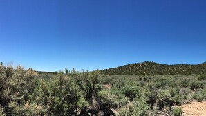 A car parked on a dirt road with a mountain in the background. - Hike By Light, Campers Delight. (Fort Garland)
