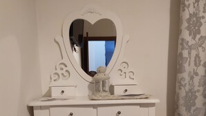 A white vanity with a heart-shaped mirror, a small refrigerator, and a decorative lantern. - Bethel Bed and Breakfast (Gela)