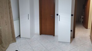 A room with a white wardrobe, a wooden door, and a tiled floor. - Bethel Bed and Breakfast (Gela)
