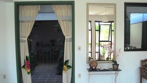 Un espacio interior con un acceso a un comedor, una ventana con vistas y una pequeña mesa con adornos.
