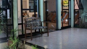 Entrada de un hotel con un banco a cuadros en el exterior, una escalera visible y un letrero para un restaurante llamado "Posod".