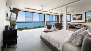 Ett modernt hotellrum med en stor säng, ett skrivbord och utsikt över havet.