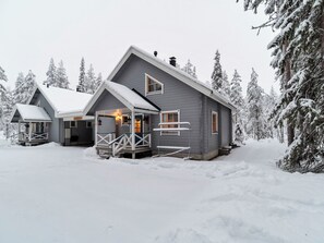 A two-story cabin with a covered porch and a visible staircase leading to the entrance.