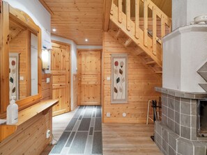 A wooden interior with a fireplace, a bench, and a staircase.