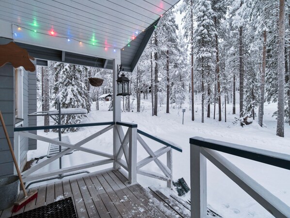 A wooden deck with a railing, a metal bucket, and a broom.