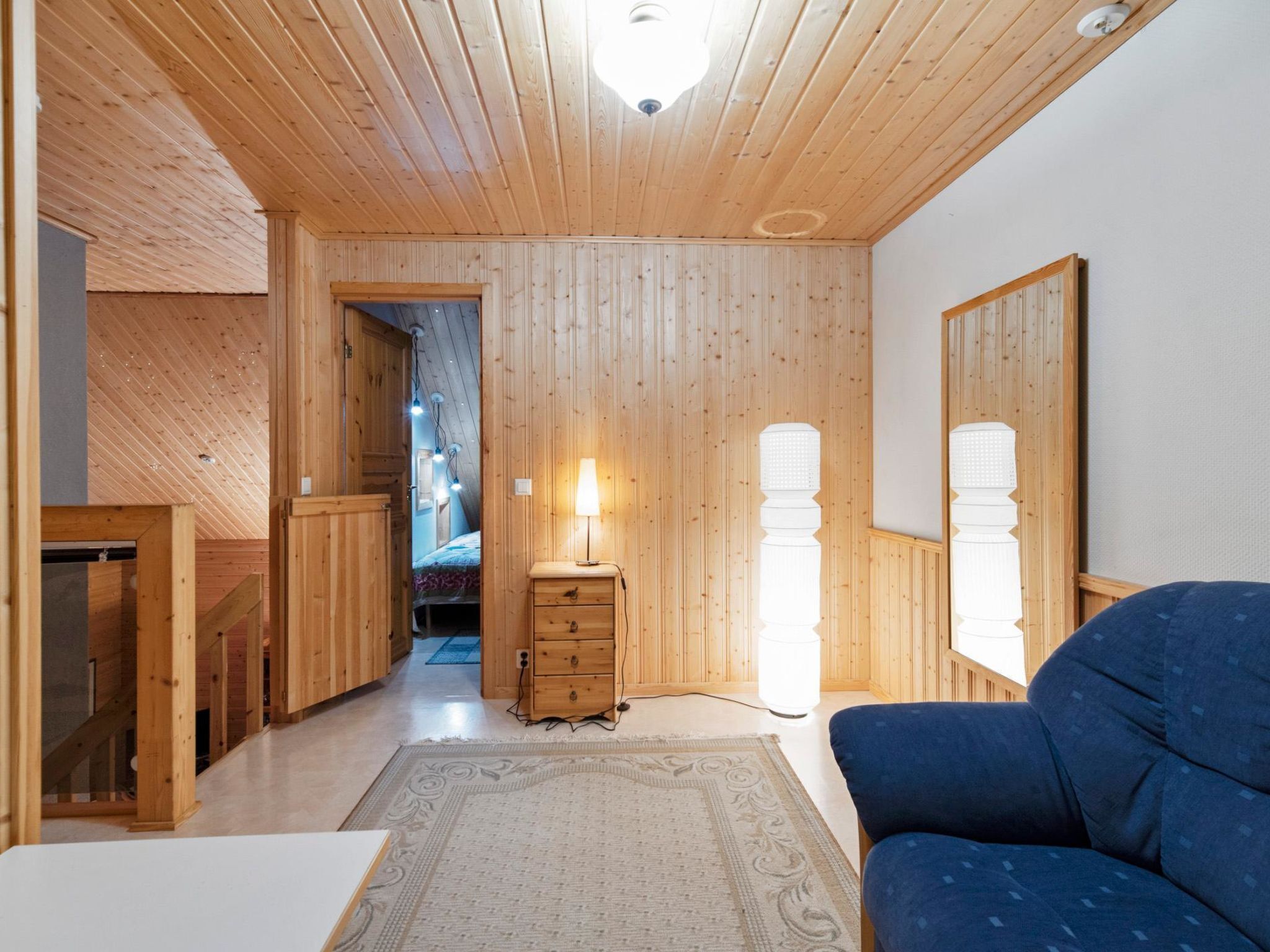 Un intérieur en bois avec un canapé, une commode et une lampe.