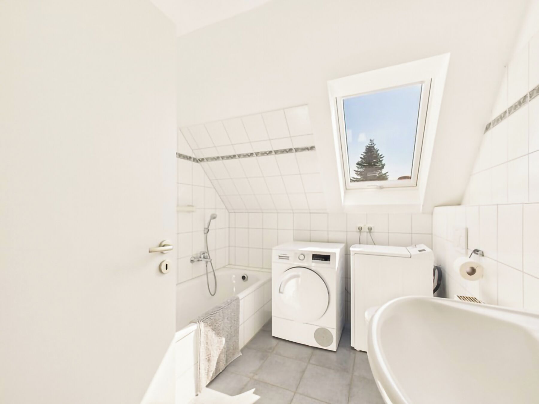 A modern bathroom with a bathtub, a shower, a washing machine, and a dryer.