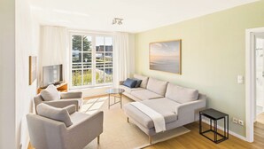 Ein modernes Wohnzimmer mit einer Sofagarnitur, einem Couchtisch und einem Fernseher.