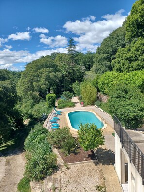 A swimming pool surrounded by lush greenery, with a clear sky above. - 120 m2 gite with private pool in a Cévennes farmhouse in the heart of nature (LAVAL-PRADEL)