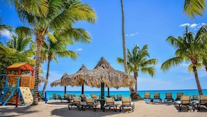 Une plage bordée de palmiers, avec une aire de jeux et des chaises de plage.