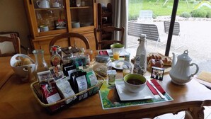 A breakfast table with various food items, a teapot, and a coffee pot. - Le Grand Noyer (Ambronay)