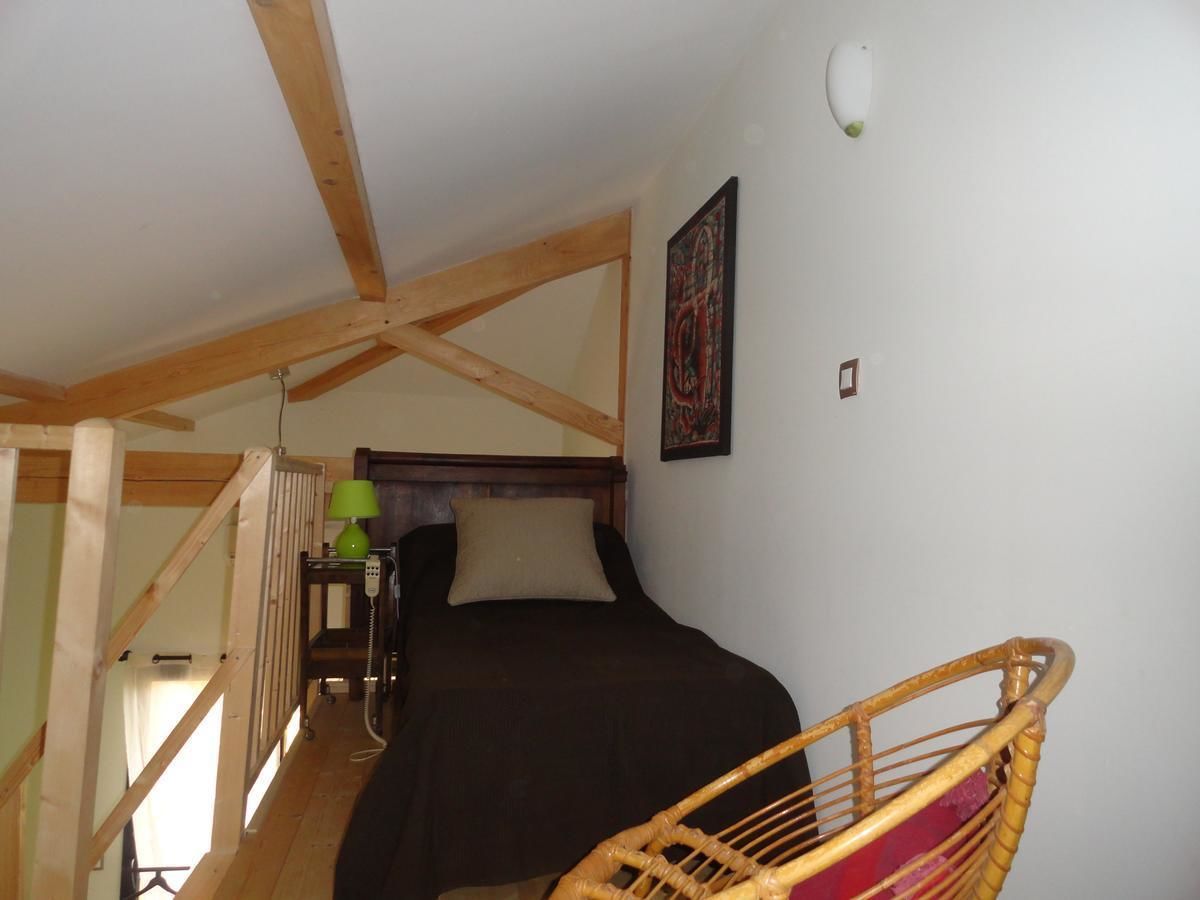 A bedroom with a bed, a chair, a lamp, and a painting on the wall.