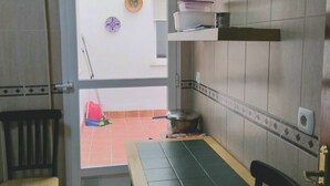 Een kleine keuken met een eettafel en stoelen, een klein raam en een betegelde spatwand.
