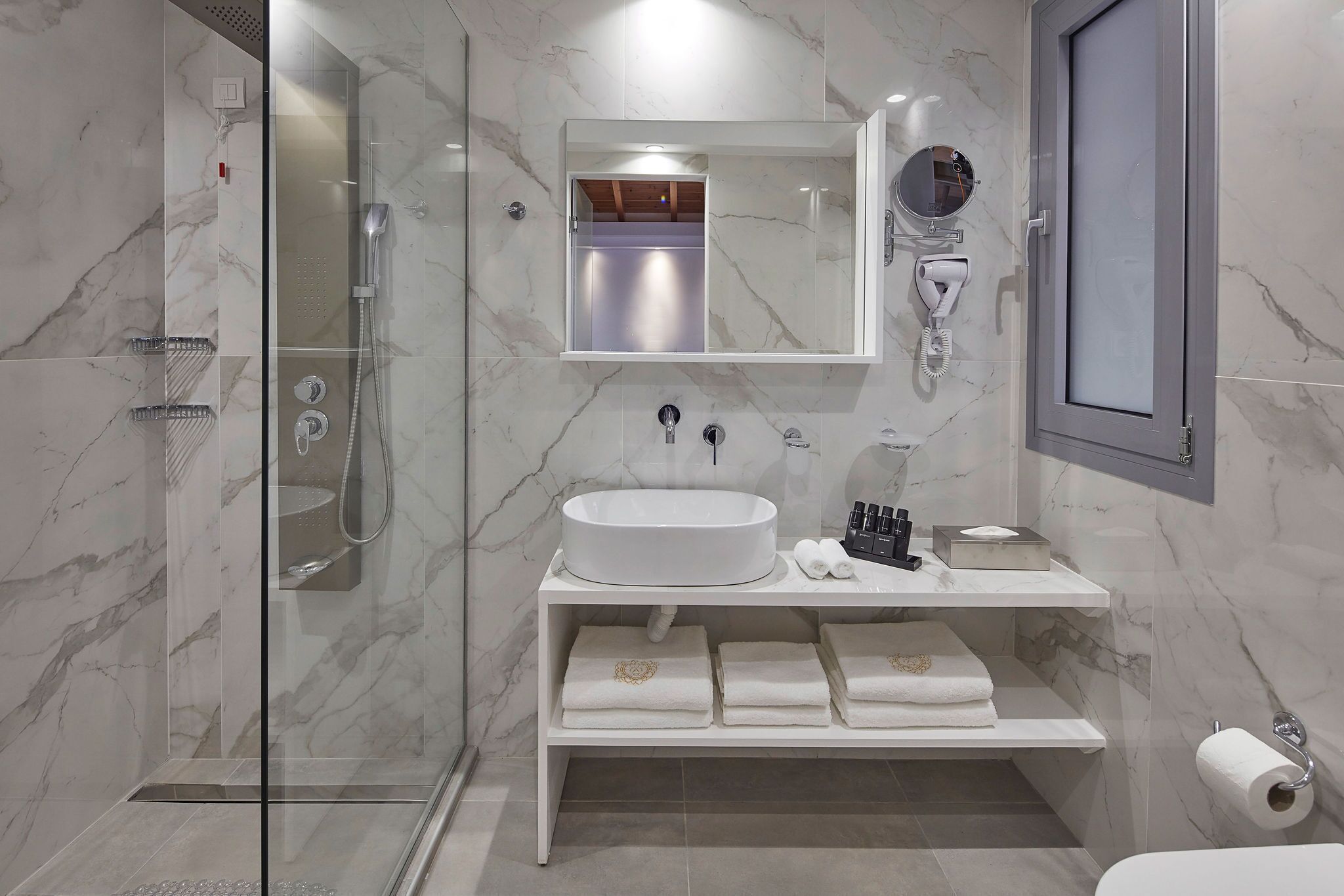 Un baño moderno con ducha de vidrio, un lavabo blanco y un espejo encima.