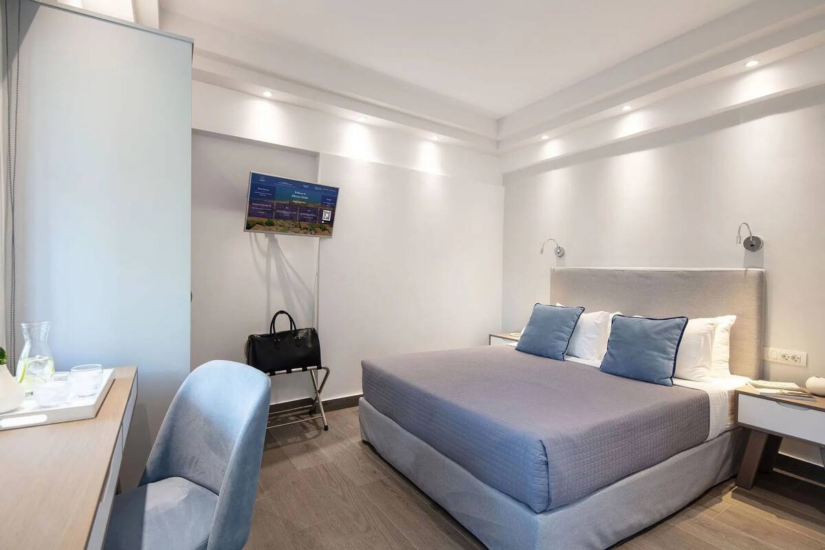 A modern hotel room with a large bed, a desk, and a chair.
