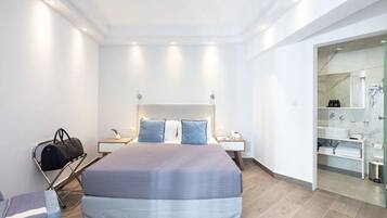 Ein modernes Hotelzimmer mit einem großen Bett, Nachttischen, einem Schreibtisch und einem durch eine offene Tür einsehbaren Badezimmer.