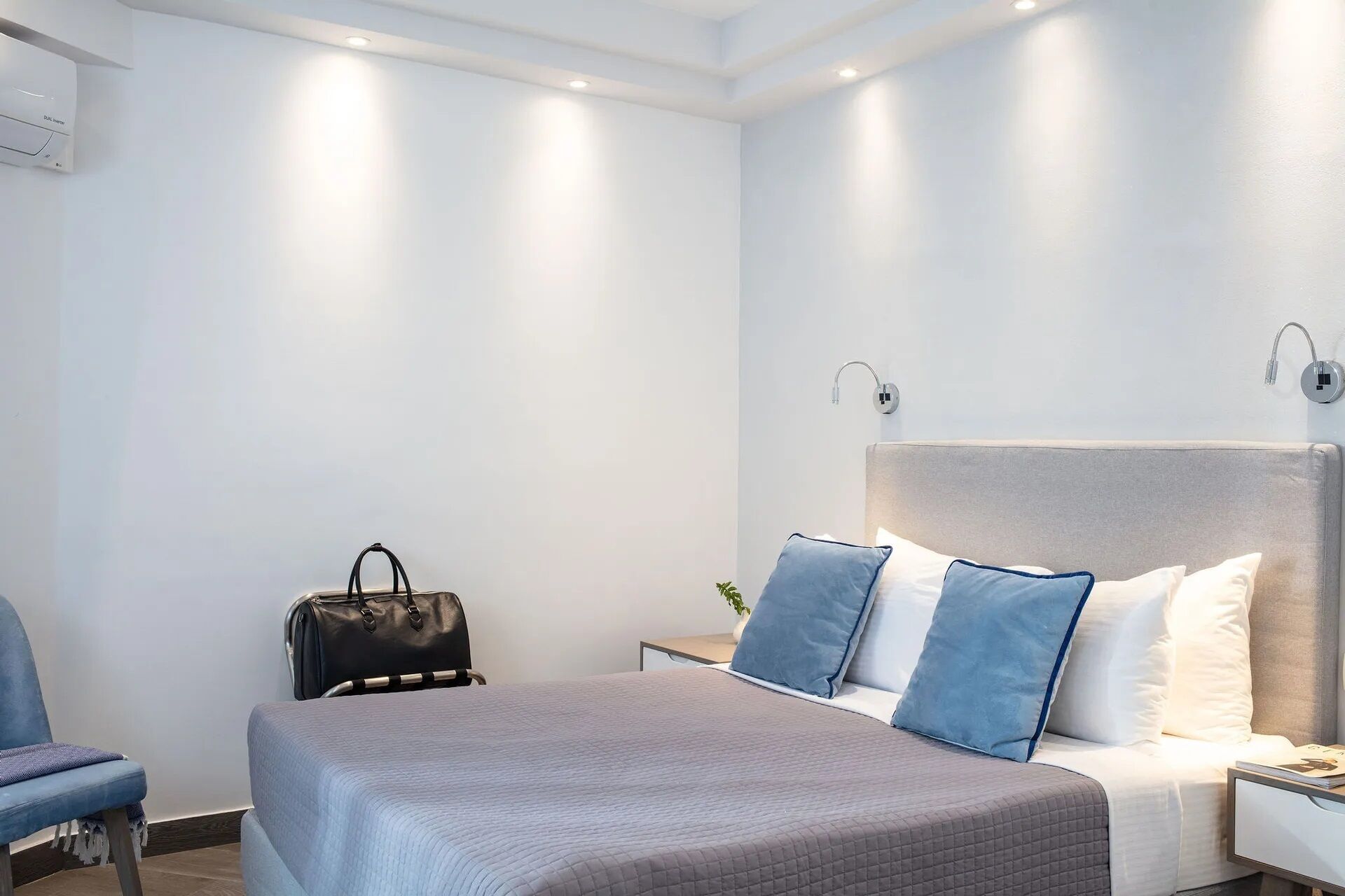 A modern hotel room with a bed, bedside table, and a chair.