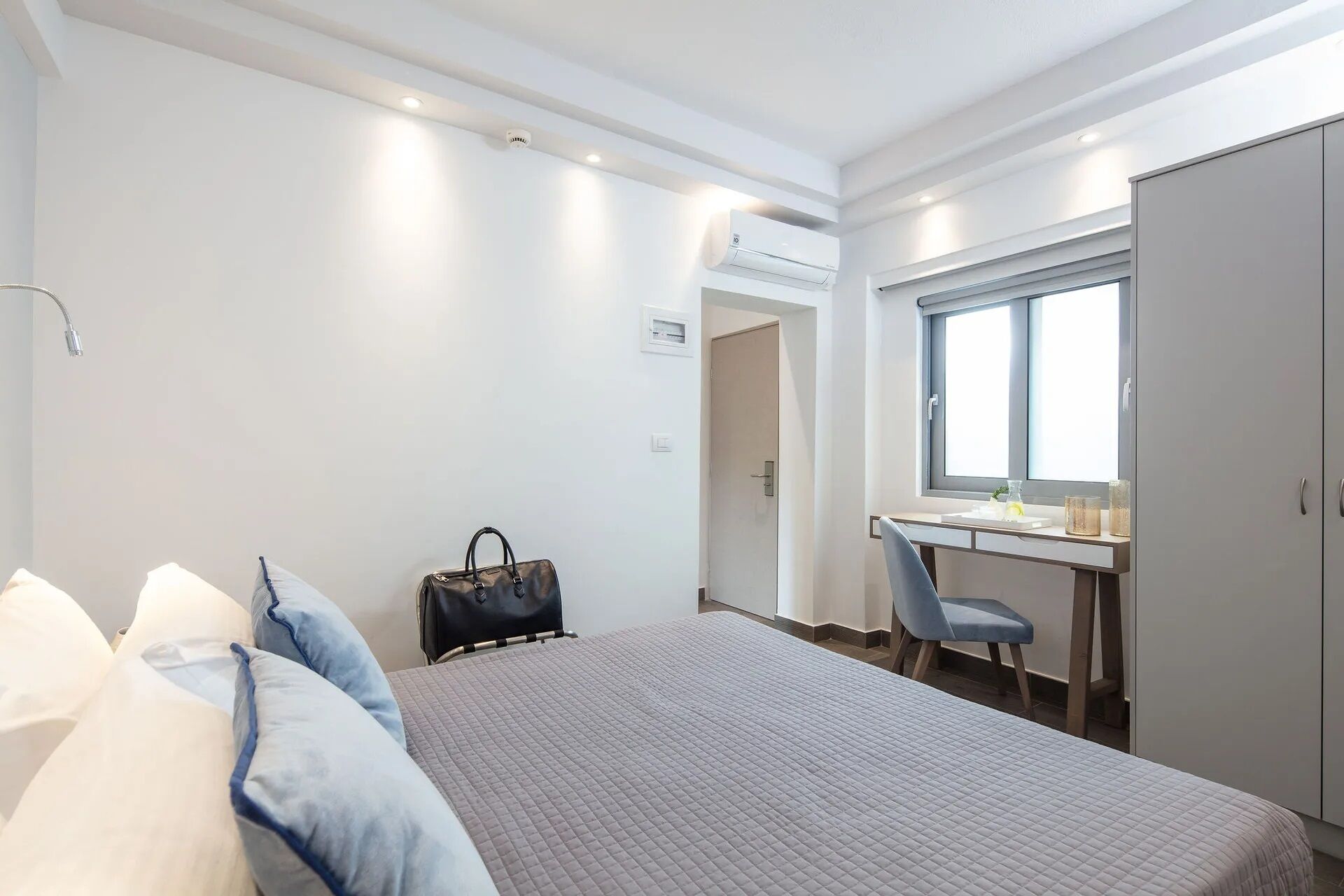 A hotel room with a bed, a desk, a chair, and a wardrobe.