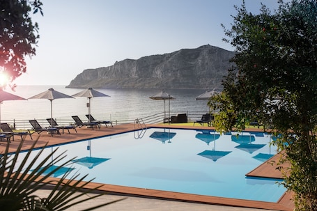 Una piscina al aire libre, sombrillas, sillones reclinables de piscina. Alkinoi Resort & Spa