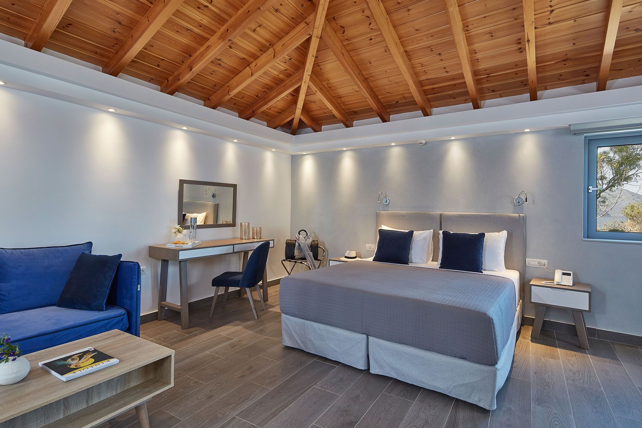 Un dormitorio moderno con una cama grande, un escritorio, una silla, un sofá y una ventana.