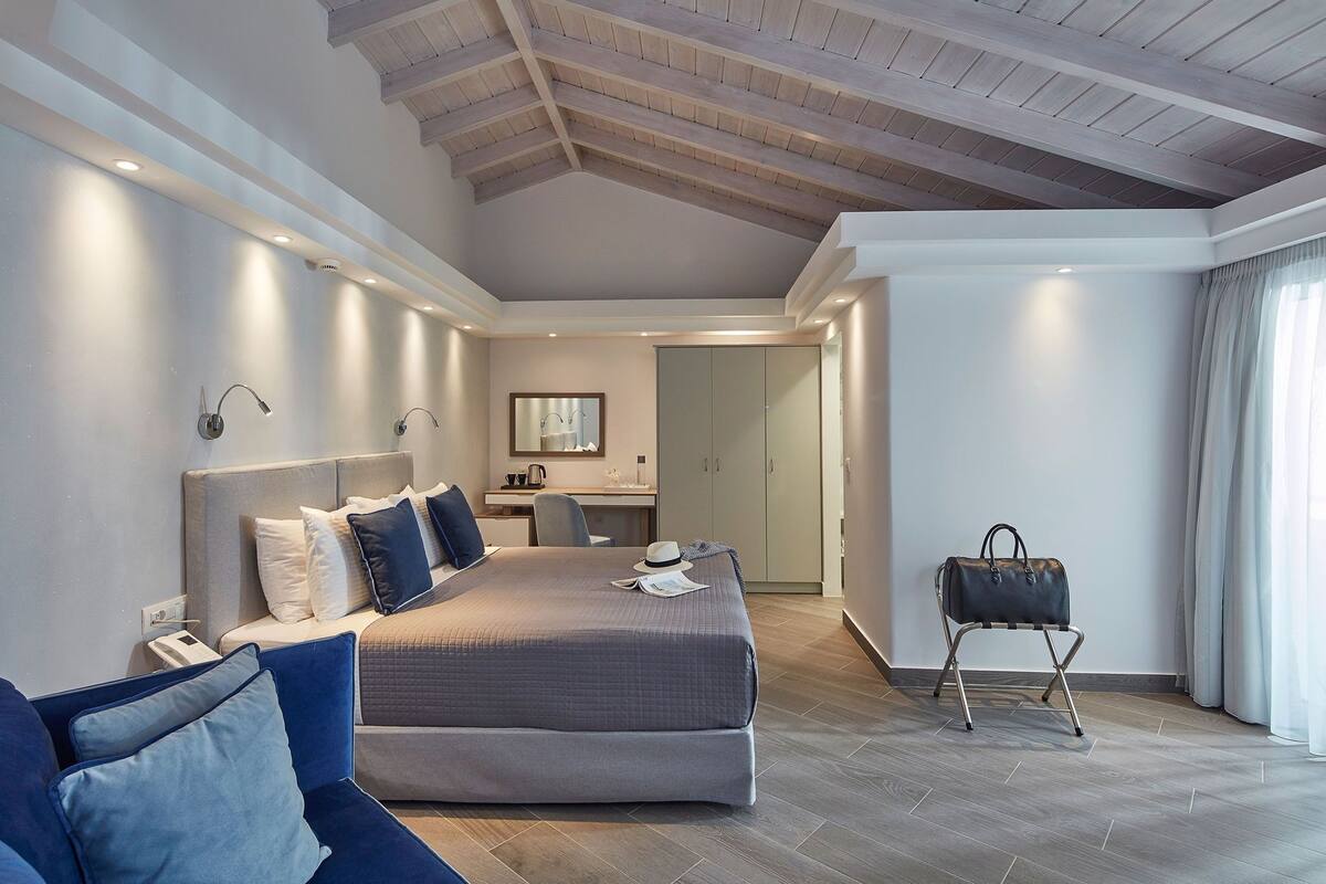 A modern bedroom with a large bed, bedside tables, a desk, and a wardrobe.