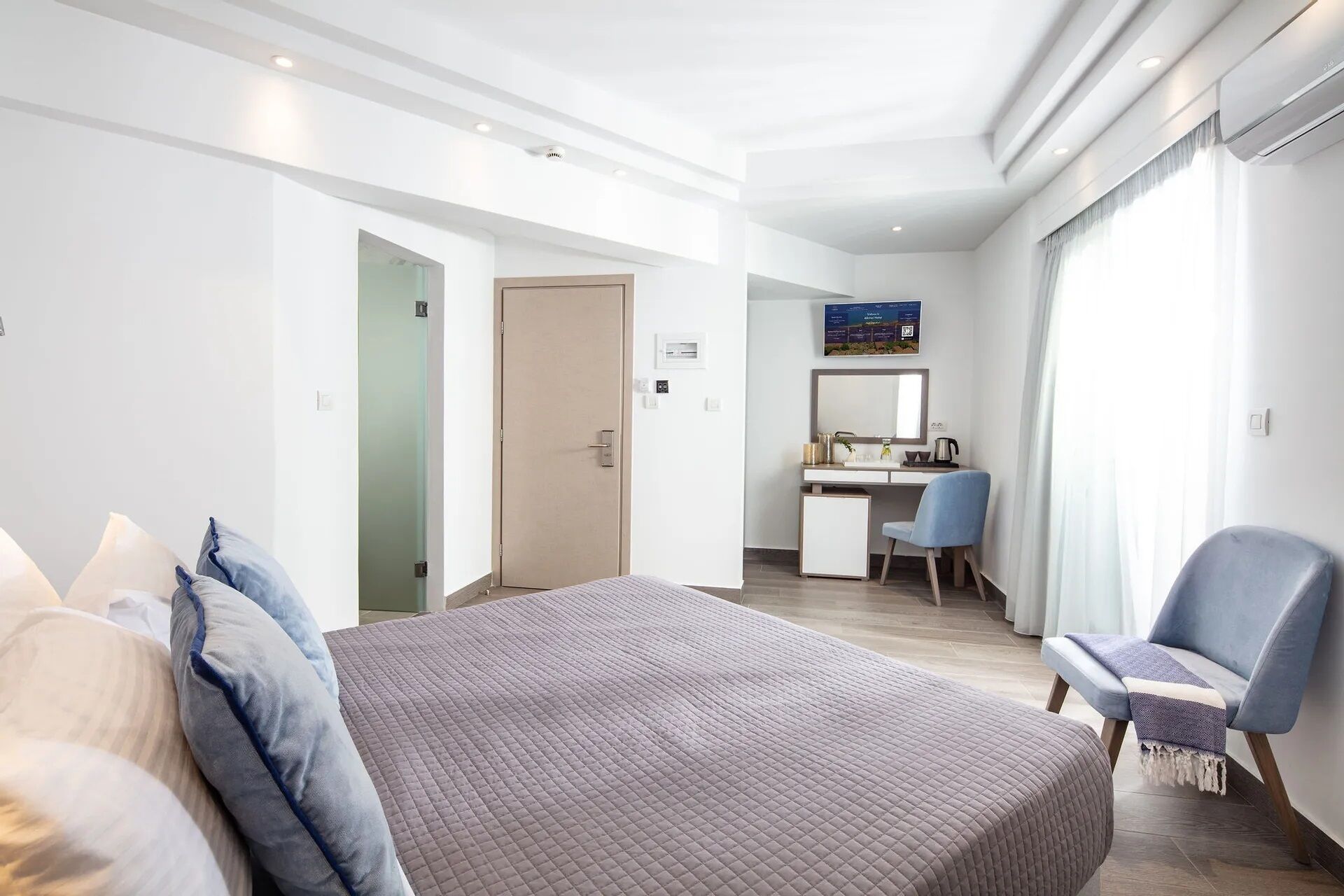 A modern hotel room with a large bed, a desk, and a chair.