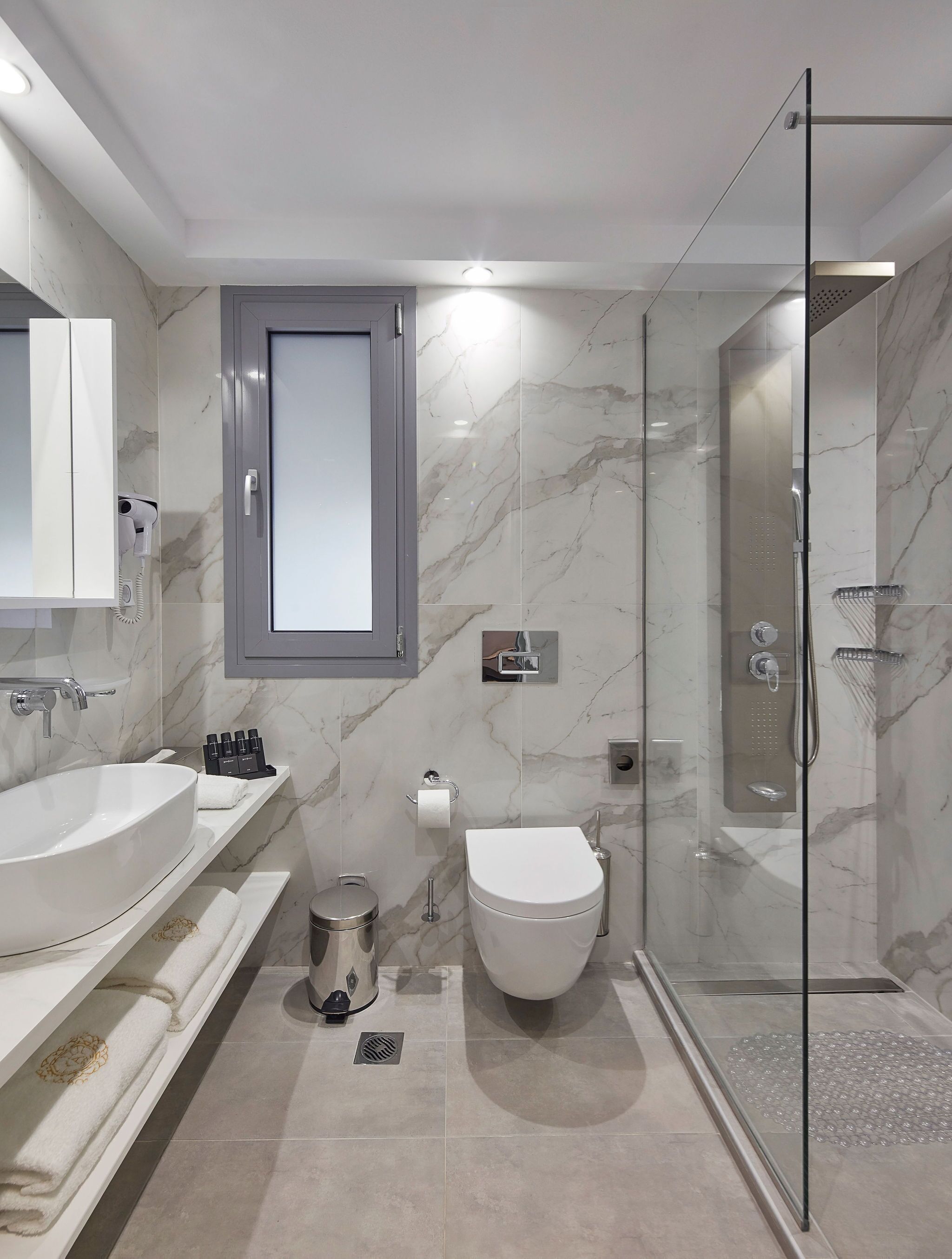 Ein modernes Badezimmer mit einer Duschkabine, einem großzügigen Waschtisch mit doppelter Spüle und einer Toilette.