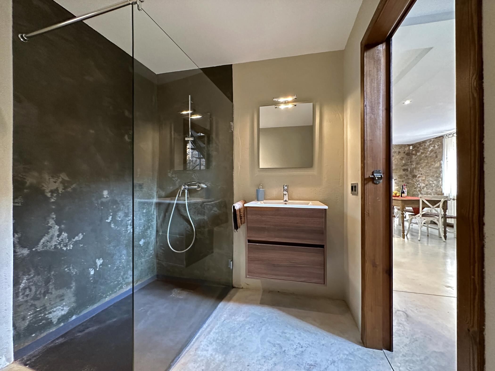 A modern bathroom with a glass-enclosed shower, a wooden vanity, and a large mirror.