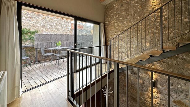 A room with a stone wall, a wooden deck, and a staircase. - Rural House La Païssa (Ullà)