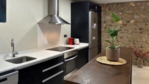 A modern kitchen with a stainless steel range hood, a built-in oven, and a refrigerator. - Rural House La Païssa (Ullà)