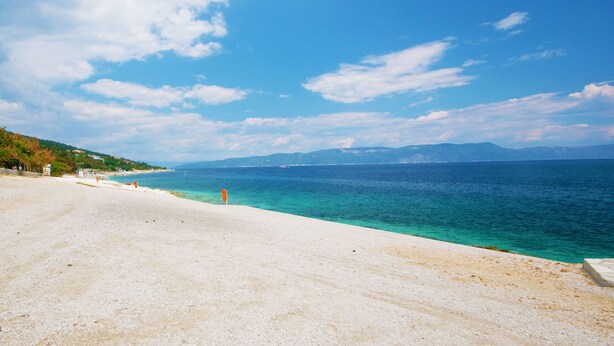 Ein Strand mit klarem türkisblauem Wasser und einem sandigen Ufer.