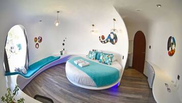 Un dormitorio moderno y curvo con una cama, una zona de estar y una mesita.