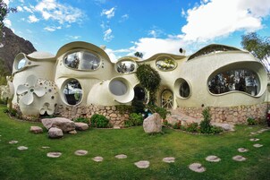 Una vivienda singular de estilo orgánico, con amplios ventanales circulares y base de piedra.