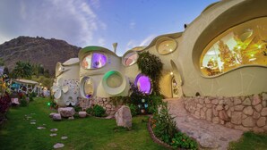 Un edificio de forma original y diseño orgánico, con amplios ventanales y un camino de piedra que conduce a la entrada.