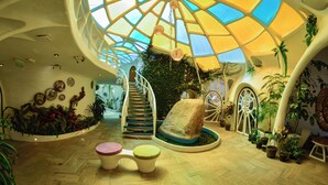 A spacious atrium with a high ceiling, a central staircase, and various potted plants. - Wifala Harmony Hotel (Urubamba)