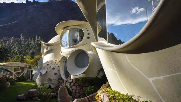 A unique architectural structure with organic shapes and circular windows, set against a mountainous backdrop. - Wifala Harmony Hotel (Urubamba)