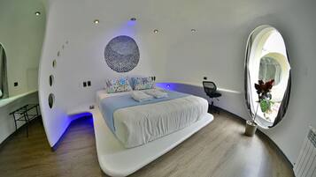 Un dormitorio moderno con un tragaluz circular, un adorno redondo en la pared y una cama con iluminación azulada.