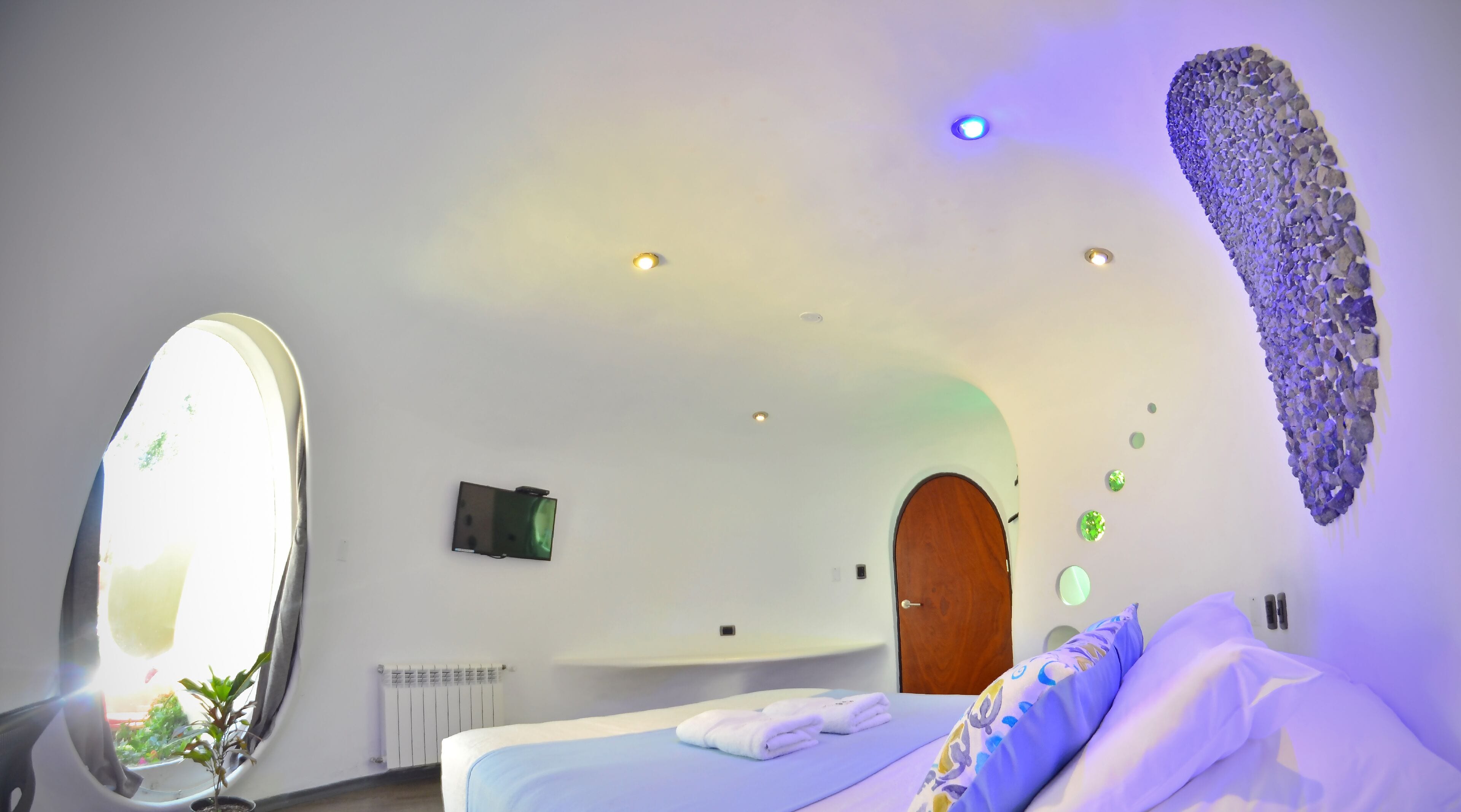 Una camera d'albergo moderna con un grande specchio, un letto con asciugamani ordinatamente piegati, una porta in legno e un decoro murale originale.