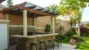 An outdoor bar area with a stone counter and four stools.