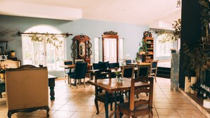 A spacious room with a large dining table, several chairs, and a variety of decorative items including plants and a mirror. - Liquidambar Hotel (Santa Lucia)