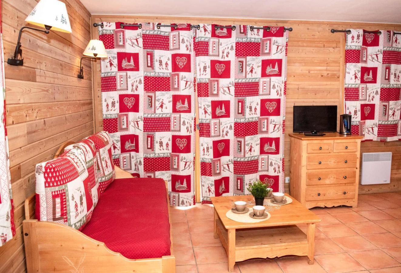 A cozy room with a wooden bed, a small table with cups, a TV, and a fireplace.