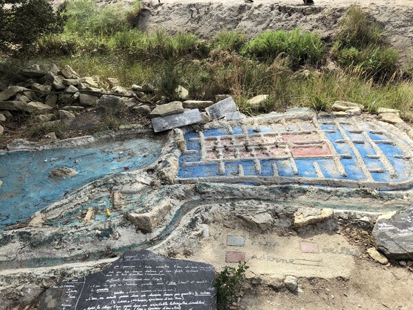 Un jaciment arqueològic a l'aire lliure amb estructures de pedra i una zona pintada de blau.